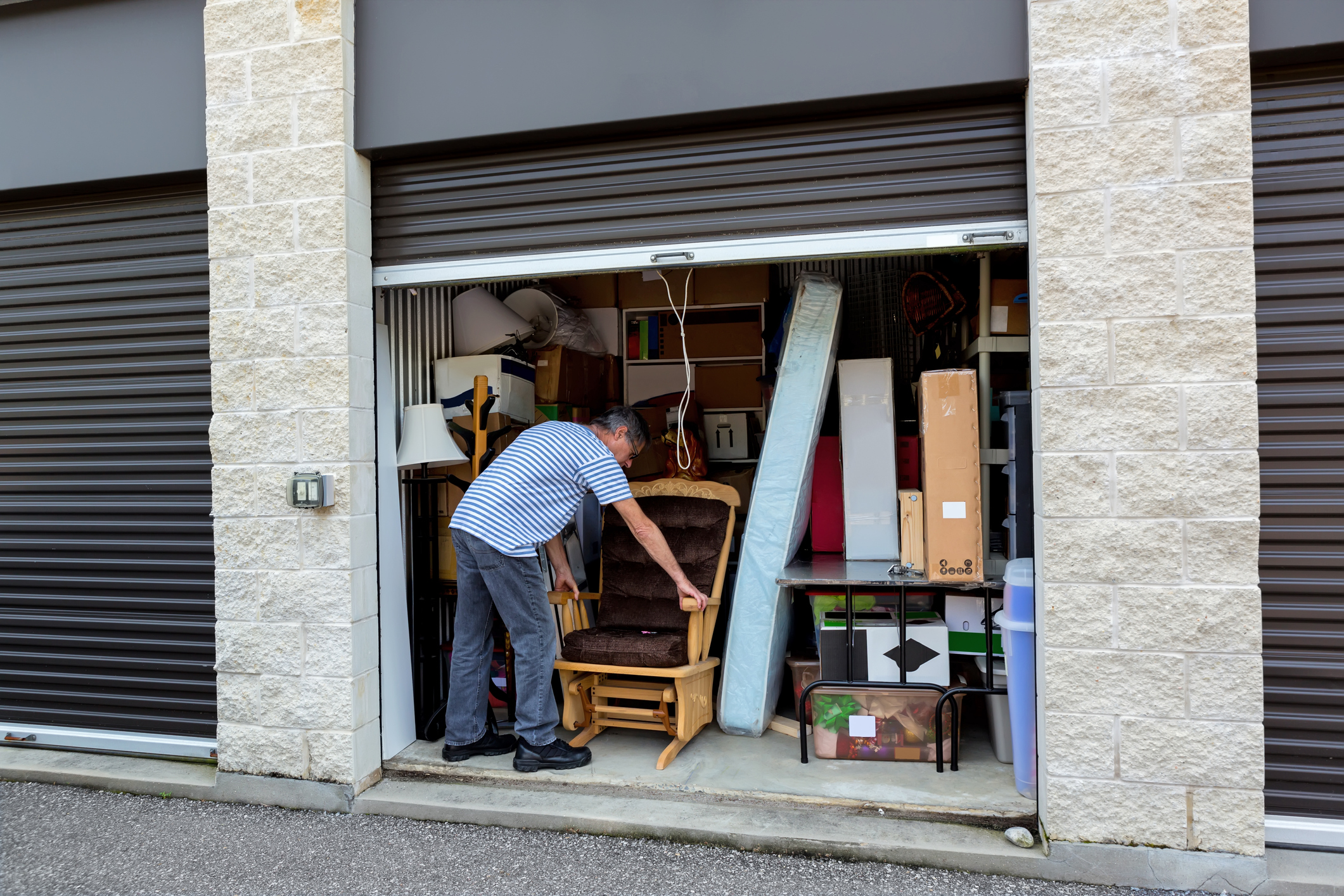 Man placing a chair in a full storage unit