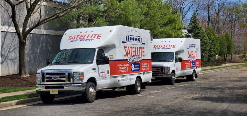 Two Satellite Self Storage moving trucks parked on the street