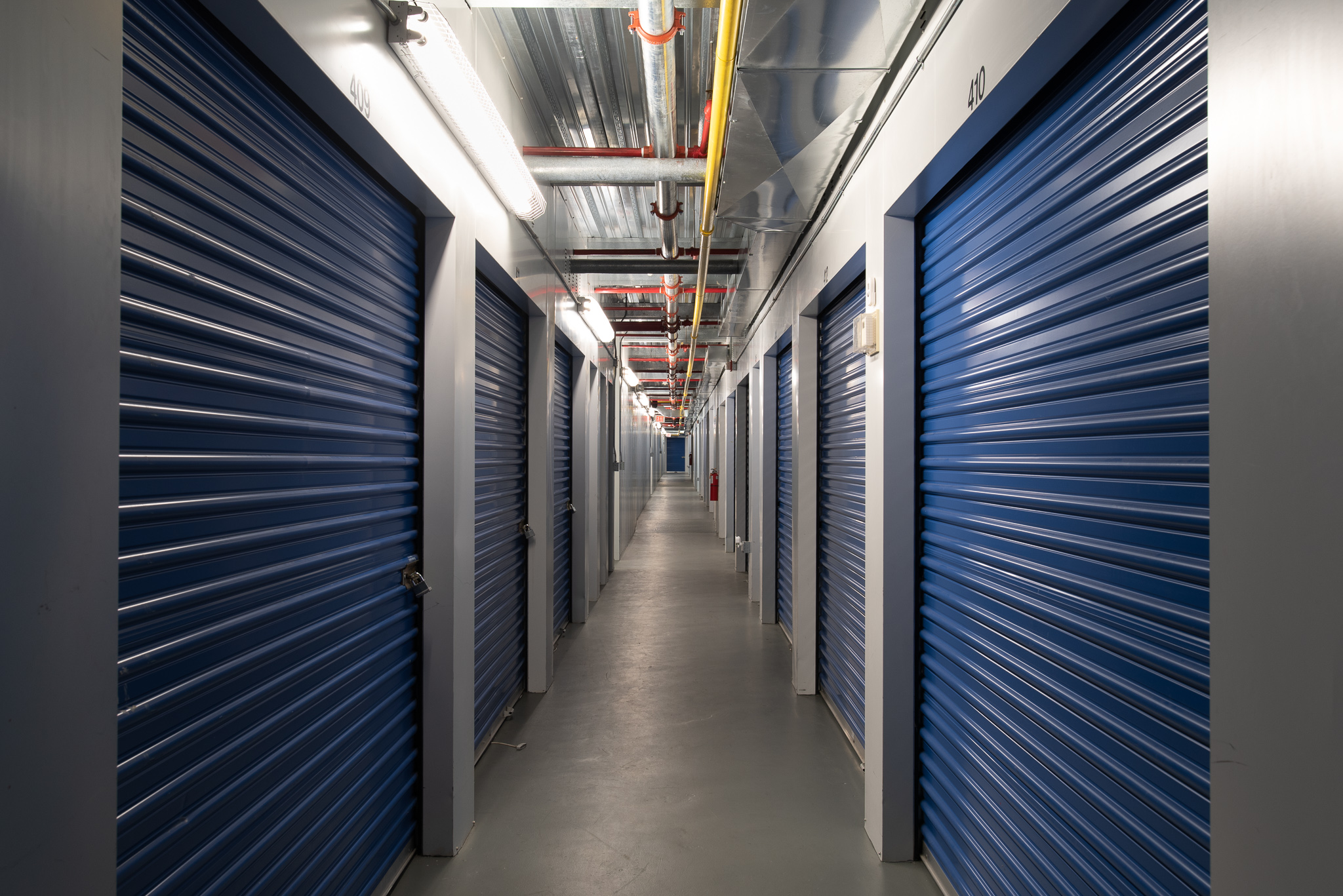 Center hallway view of storage units with blue doors inside Middletown Location